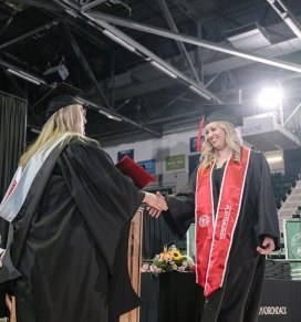 A SUNY Plattsburgh graduate receives a diploma at commencement