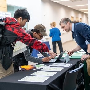 Assistant Director of Student Success Brian Holtz helps students register at a job fair.