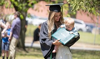 A graduate holds an infant after the ceremony