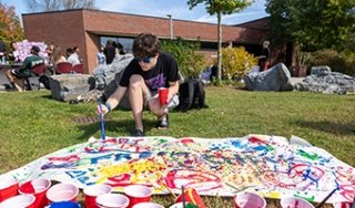 A student paints a mural during Fresh Check Day