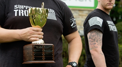 Closeup of a veteran holding a plaque commending the Veterans Club