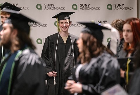 A graduate smiles at the camera before the ceremony