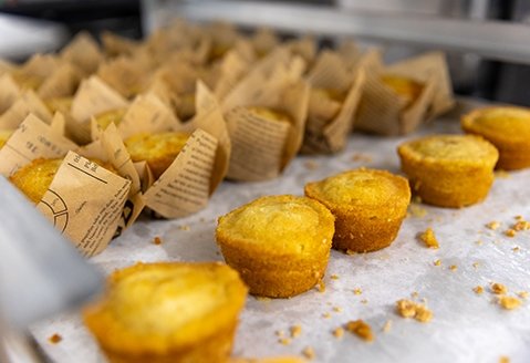 Cornbread muffins are shown in a row on a countertop