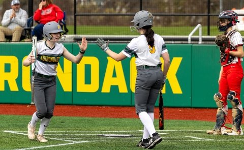 Softball players slap a high-five during a game in the 2025 season.