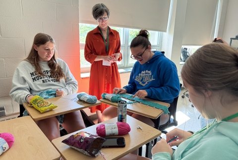 SUNY Adirondack Networking and Cybersecurity instructor Anne Wojtowecz teaches Upward Bound students how to crochet