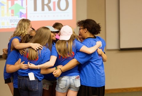 A group of Upward Bound students stand in a group hug