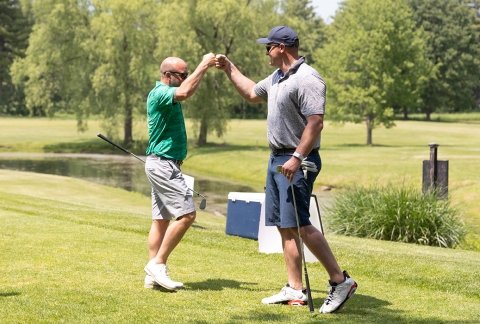 Two golfers slap high five at the Beeman Golf Tournament